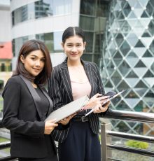 Close up of two Business woman looking with paper document together while walking to office. Business people concept.