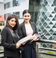 Close up of two Business woman looking with paper document together while walking to office. Business people concept.